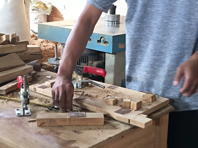 Vertical machine shaping a wooden part, held by hand